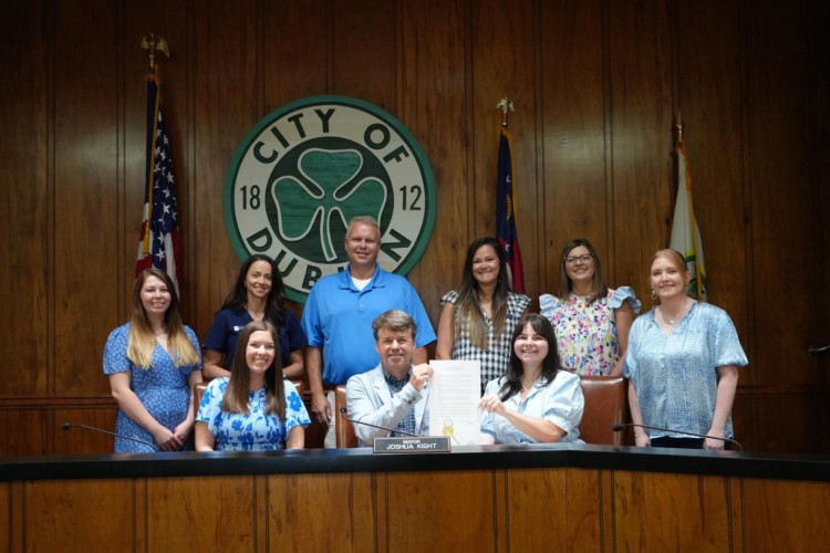 Group photo of mayor and stepping stones staff holding up the proclamations signed on a piece of paper.